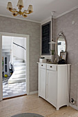 Cabinet against grey wallpaper with view into hallway with chequered floor