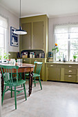 Old table and chairs in retro kitchen with olive-green cabinets