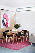 Dining table and chairs with black leather, designer lamp above, picture with rooster motif on the wall