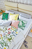 A double bed with floral bed linen and cushions