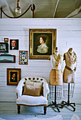 Dressmakers, armchairs and gold frame pictures on white painted wooden wall