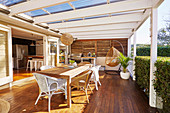Wooden terrace with dining table, wicker furniture and outdoor kitchen
