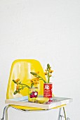 Tin cans used as vases on tray and yellow chair