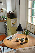 Laptop, houseplant and small globe on round table below pendant lamp