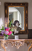 Bust and vase of flowers on carved, antique console table
