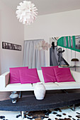 Hot-pink cushions on modern white sofa in eclectic living room