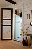 Panelled door with floral wallpaper leading into kitchen