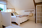 Bett im Schlafzimmer neben dem Treppenaufgang unter der Dachschräge