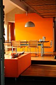 Dining table in front of orange wall on raised platform