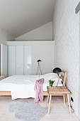 Schlichte Holzmöbel im Schlafzimmer mit weißer Backsteinmauer