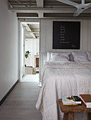 Double bed against white-painted board wall in loft apartment