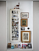Knick-knacks in display case and old pictures in niche