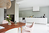 Chairs with pastel upholstery in front of modern open-plan kitchen