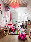 Kinderzimmer mit buntem Teppich, Baldachin-Bett und auf dem Boden spielendem Mädchen