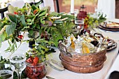 Various drinks in vintage tub, crayfish and flower arrangement on set table