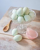 Eggs dyed mint-green in glass bowl on rustic wooden table