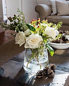 Wintry arrangement of white roses and pine cones