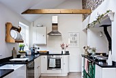 Black and white country-house kitchen with sloping ceiling and wooden beam