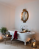 Romantic arrangement of candles around free-standing bathtub