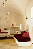 Weiß getünchte Lounge mit roten Farbakzenten und Gewölbedecke in einem renoviertem Trullo