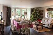 Table set for Christmas dinner and decorated Christmas tree in traditional country-house living room