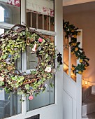 Wreath with dried apple slices on front door and garland with slices of oranges on handrail of staircase
