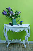 Verschnörkelter Konsolentisch mit Blumendeko vor knallgrüner Wand