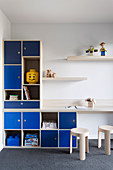 Shelf system with blue fronts and integrated table top in the boy's room