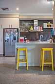Modern kitchen with yellow stools and blackboard on the wall