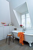 Frei stehende Badewanne, Hocker und Einbauschrank mit Ablage in weißem Badezimmer mit Gaubenfenster