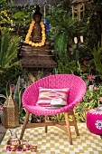 Pink wicker armchair and colourful decorations on rug in garden