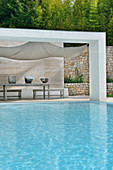Roofed terrace with stone back wall next to pool