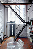 Metal staircase leading to gallery in high-ceilinged narrow room
