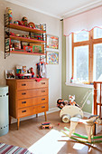 Shelves above wooden chest of drawers in vintage-style nursery