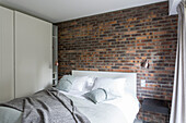 Double bed and fitted wardrobes in bedroom with vintage brick wall