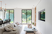 Fitted cupboards incorporating TV, coffee table and sofa in living room with floor-to-ceiling windows overlooking garden