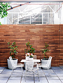 Table with chairs and plant pots in the courtyard with wooden privacy screen