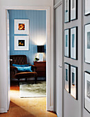 Hallway with framed photos and view of armchairs in the bedroom