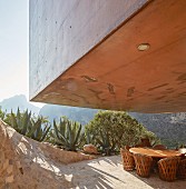 Concrete house projecting over round table on terrace with panoramic view