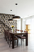 Dining table and upholstered chairs in front of cantilever stairs on wall with patterned wallpaper