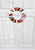 Circular door wreath made from colourful satin ribbons with Merry Christmas motto