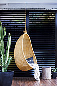 Hammock chair made of basket against a black slat wall