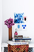 Pile of books and pink hydrangeas against a blue mood board