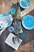 Wooden table set with blue plates in sunshine