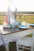 Romantisch gedeckter Tisch auf der Wiese vor einem Tipi