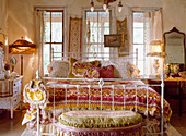 Lavish textiles on old metal bed in romantic bedroom