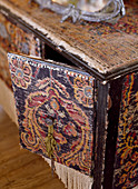 Detail of black cabinet covered with pieces of old carpet