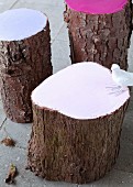 Various tree-stump stools with ends painted in pastel colours and white bird figurine