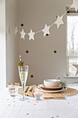 Garland of stars above table set in natural shades and with natural materials