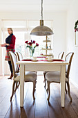 Woman walking behind white dining table with Baroque chairs